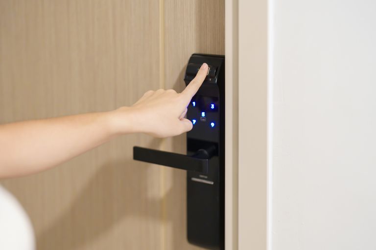 Hand using fingerprint scan for smart digital door lock while open or close the door at home or apartment. NFC Technology, keycard, PIN number, smartphone and contactless lifestyle concepts